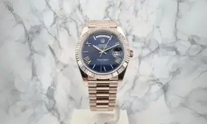 En lyxig Rolex Day-Date med blå urtavla och gulddetaljer, ett perfekt exempel på schweizisk tillverkning.