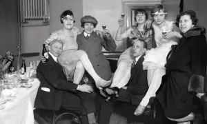 Festligt sällskap i mode 1920-tal, med kvinnor i klänningar och män i kostym, skålar och njuter av festen.