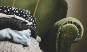 En hög med kläder ligger på en grön soffa. Kanske dags för lite dry clean hemma?