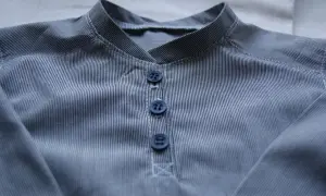Detaljerad vy av en randig skjorta med krage och tre mörkblå knappar.