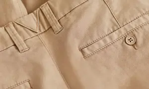 Detaljbild på beige chinos med snygga sömmar och en knapp. Perfekt bas för många olika skor till chinos.