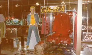Reklam för GULBLA med en man i jeans, gul t-shirt och blå jacka. Röd jacka och byxor visas också.