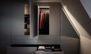 En modern garderob med belysta kläder och vikta textilier. Den stilrena designen är mode just nu.