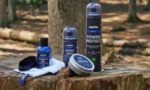 Produkter för impregnering av syntetskor: rengöringsgel, sprayvax, power protect och wax oil, placerade på en trädstubbe i skogen.