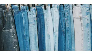 En rad blå jeans hänger på galgar, redo att stryka. Olika nyanser av denim, från mörkblått till ljusblått, skapar en visuell fest.