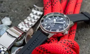 Orient Star dykare med svart gummiarmband och ett extra länkarmband. Rött rep i bakgrunden.