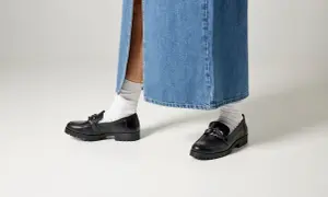 Svarta loafers med kedja och vita strumpor till dam. Perfekt för en trendig look.
