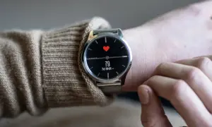En person bär en elegant Garmin-klocka med en röd hjärtsymbol och puls på skärmen. En av de bästa herrklockor för den hälsomedvetne.