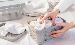 Händer organiserar rullade handdukar i en korg. Som att vika t-shirt, men för badrummet.