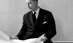Man i kostym från mode 1950-talet granskar ritningar.