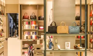 Ett skyltfönster med väskor och skor från italienska modehus. Lyxiga accessoarer visas upp i en elegant butiksmiljö.