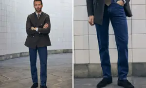 Man i mörk kavaj och blå jeans, med armarna i kors. En stilren kombination för en modern look.