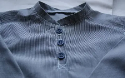 Detaljerad vy av en randig skjorta med krage och tre mörkblå knappar.