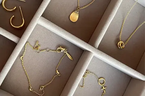 Ett urval av eleganta guld smycken herr: örhängen, halsband med hängsmycken och ett armband med hjärtan.