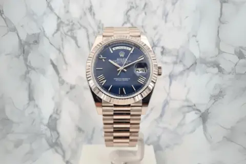 En lyxig Rolex Day-Date med blå urtavla och gulddetaljer, ett perfekt exempel på schweizisk tillverkning.