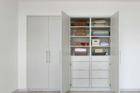 En öppen garderob med snygg förvaring av kuddar, filtar, korgar och lådor. Perfekt garderob inspo för ett organiserat hem.