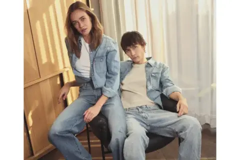 Ett par i helblått, en trendig double denim-look. Hon bär en jeansskjorta och jeans, han en jeansskjorta och jeans.