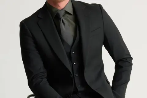 Man i svart kostym med svart skjorta och slips. Elegant och stilren klädsel.