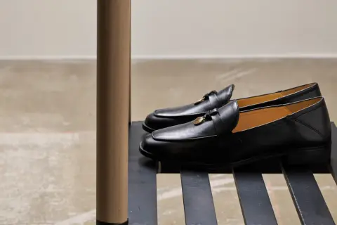 Eleganta svarta loafers till kostym, med gulddetaljer. Perfekta för en stilfull look.