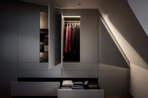 En modern garderob med belysta kläder och vikta textilier. Den stilrena designen är mode just nu.