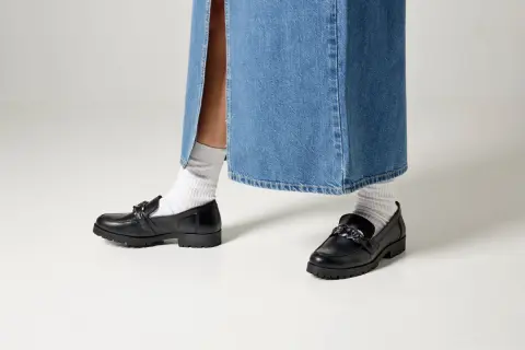 Svarta loafers med kedja och vita strumpor till dam. Perfekt för en trendig look.