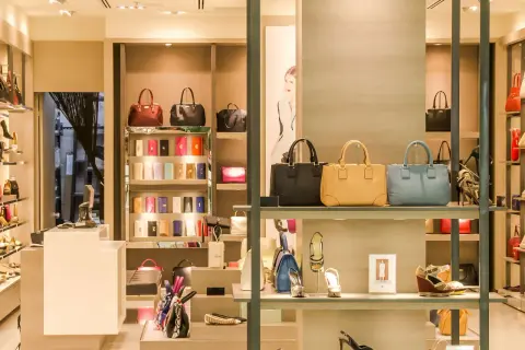 Ett skyltfönster med väskor och skor från italienska modehus. Lyxiga accessoarer visas upp i en elegant butiksmiljö.