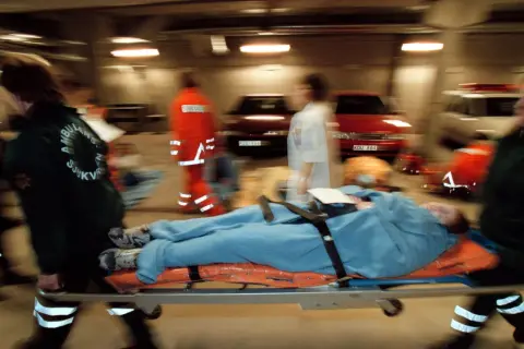 Ambulanspersonal bär en patient på bårbil. Tänk om dragkedja uppfinnare kunde se hur snabbt de arbetar.