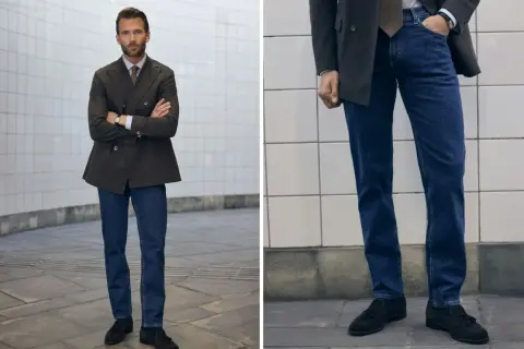 Man i mörk kavaj och blå jeans, med armarna i kors. En stilren kombination för en modern look.
