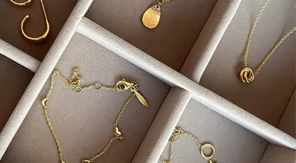 Ett urval av eleganta guld smycken herr: örhängen, halsband med hängsmycken och ett armband med hjärtan.