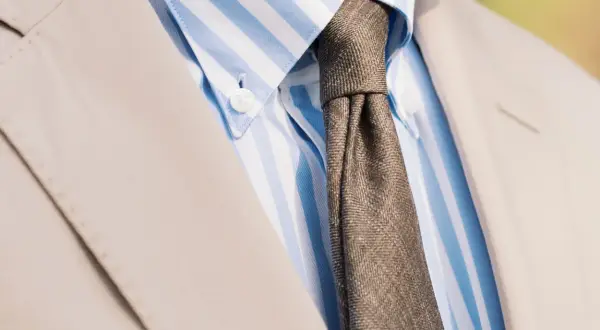 En brunmelerad slips till en ljusblårandig skjorta och en beige kostym. Klassisk stil för alla tillfällen.