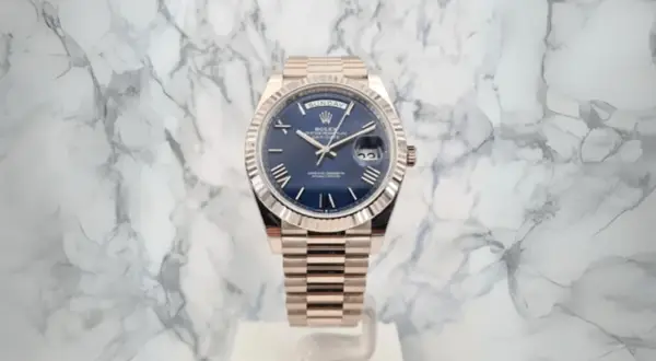 En lyxig Rolex Day-Date med blå urtavla och gulddetaljer, ett perfekt exempel på schweizisk tillverkning.