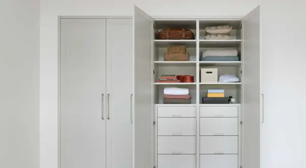 En öppen garderob med snygg förvaring av kuddar, filtar, korgar och lådor. Perfekt garderob inspo för ett organiserat hem.