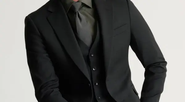 Man i svart kostym med svart skjorta och slips. Elegant och stilren klädsel.