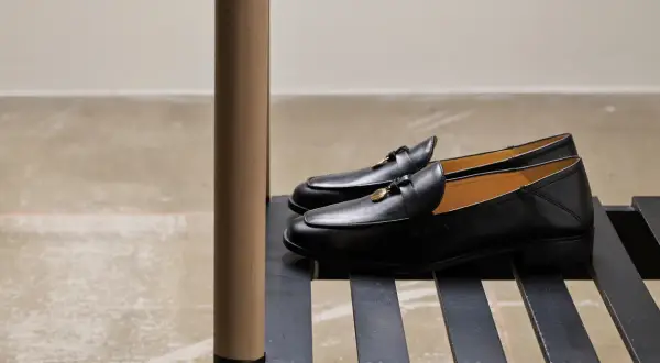 Eleganta svarta loafers till kostym, med gulddetaljer. Perfekta för en stilfull look.