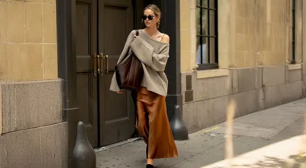 En kvinna går på gatan i en elegant outfit där brunt och svart ihop skapar en sofistikerad look.
