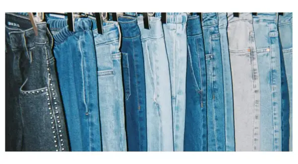 En rad blå jeans hänger på galgar, redo att stryka. Olika nyanser av denim, från mörkblått till ljusblått, skapar en visuell fest.