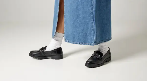 Svarta loafers med kedja och vita strumpor till dam. Perfekt för en trendig look.
