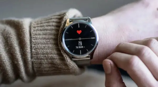 En person bär en elegant Garmin-klocka med en röd hjärtsymbol och puls på skärmen. En av de bästa herrklockor för den hälsomedvetne.