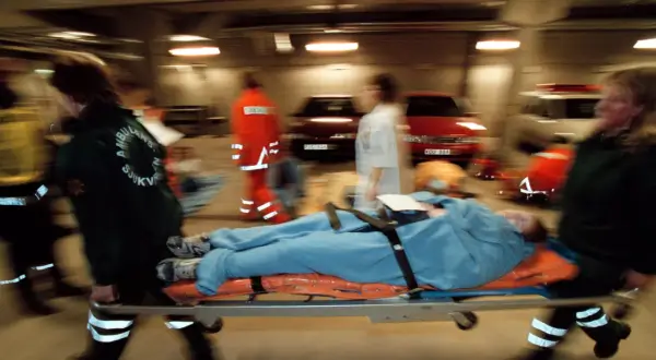 Ambulanspersonal bär en patient på bårbil. Tänk om dragkedja uppfinnare kunde se hur snabbt de arbetar.