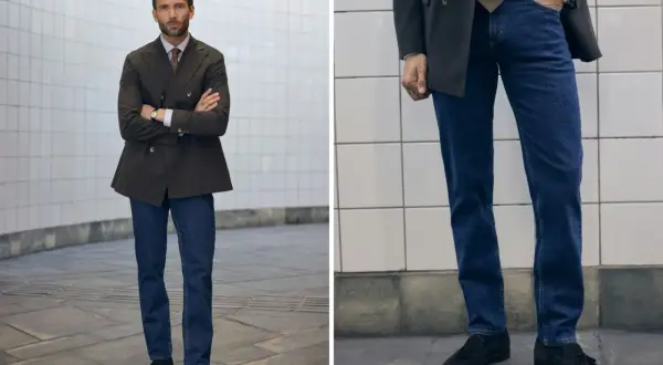 Man i mörk kavaj och blå jeans, med armarna i kors. En stilren kombination för en modern look.