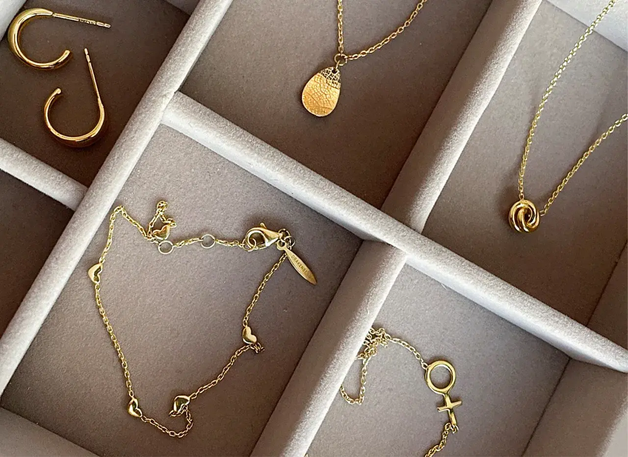 Ett urval av eleganta guld smycken herr: örhängen, halsband med hängsmycken och ett armband med hjärtan.