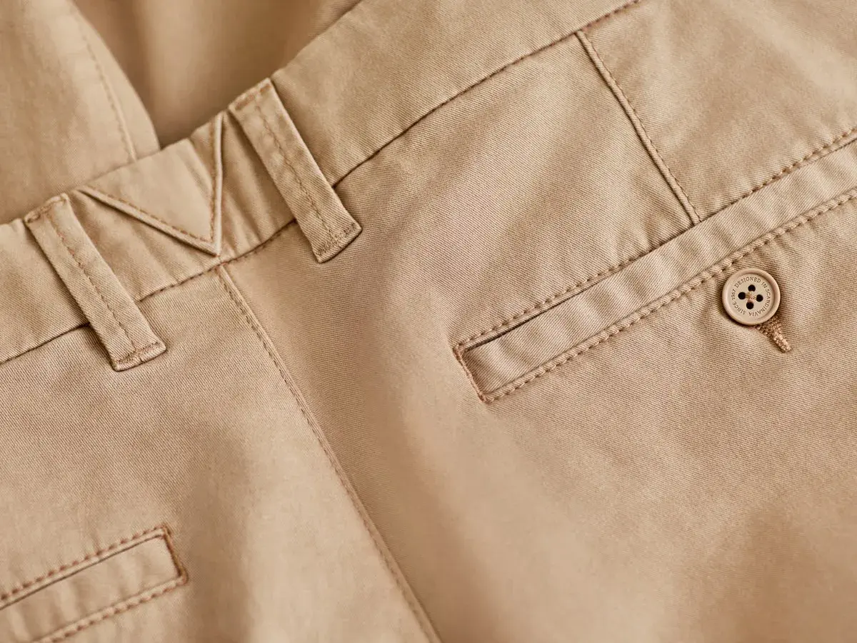 Detaljbild på beige chinos med snygga sömmar och en knapp. Perfekt bas för många olika skor till chinos.