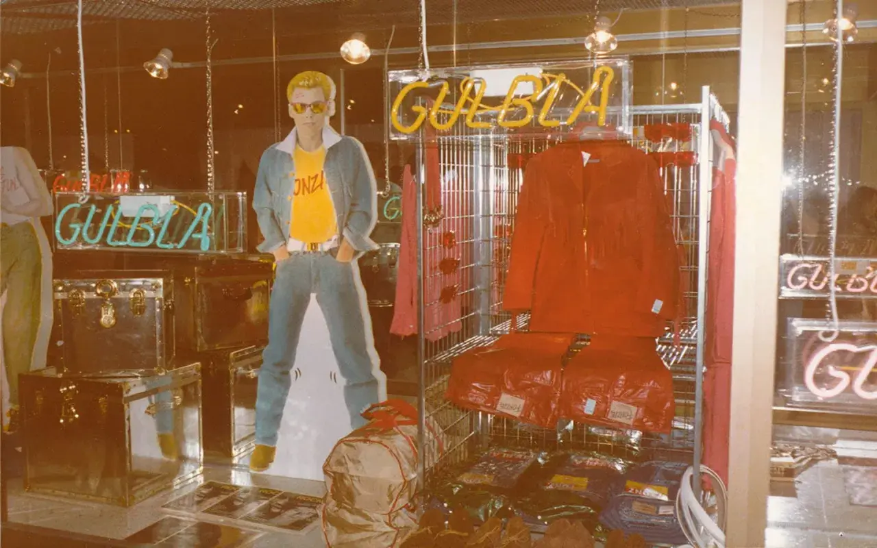 Reklam för GULBLA med en man i jeans, gul t-shirt och blå jacka. Röd jacka och byxor visas också.