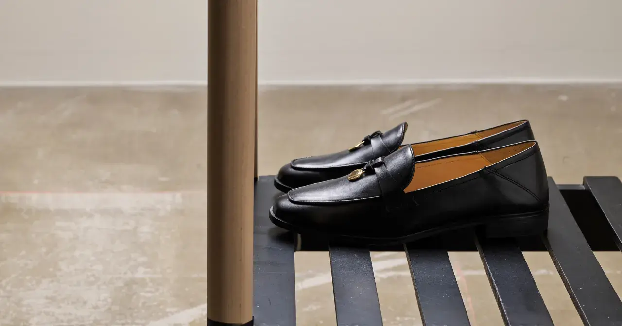 Eleganta svarta loafers till kostym, med gulddetaljer. Perfekta för en stilfull look.