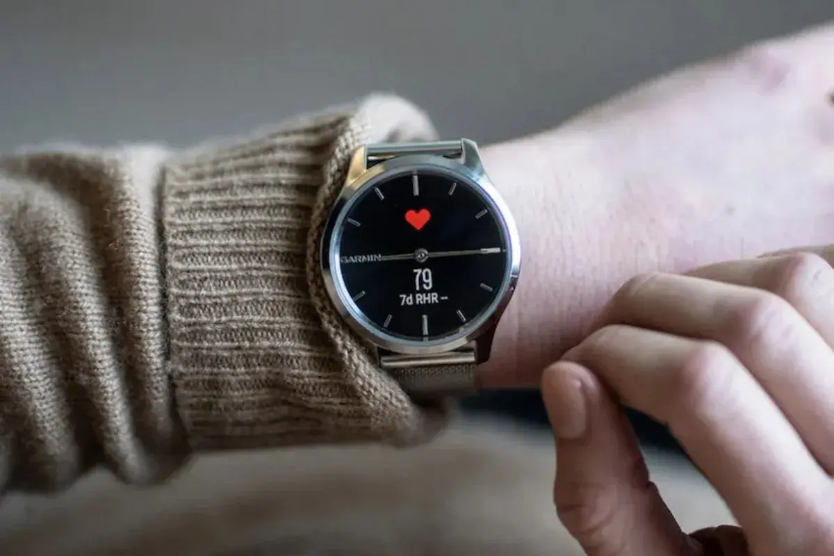 En person bär en elegant Garmin-klocka med en röd hjärtsymbol och puls på skärmen. En av de bästa herrklockor för den hälsomedvetne.