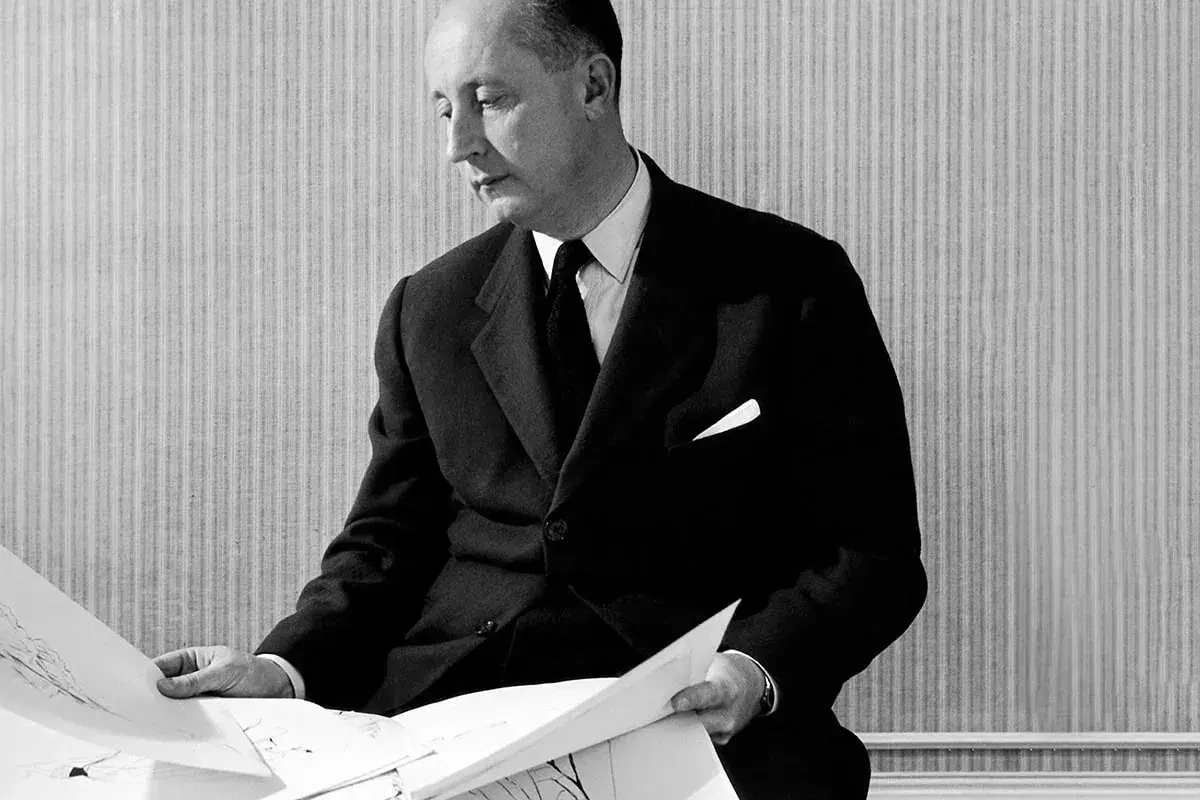 Man i kostym från mode 1950-talet granskar ritningar.
