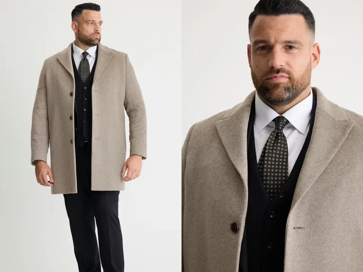 Man i beige jacka till kostym, med svart väst och mönstrad slips.