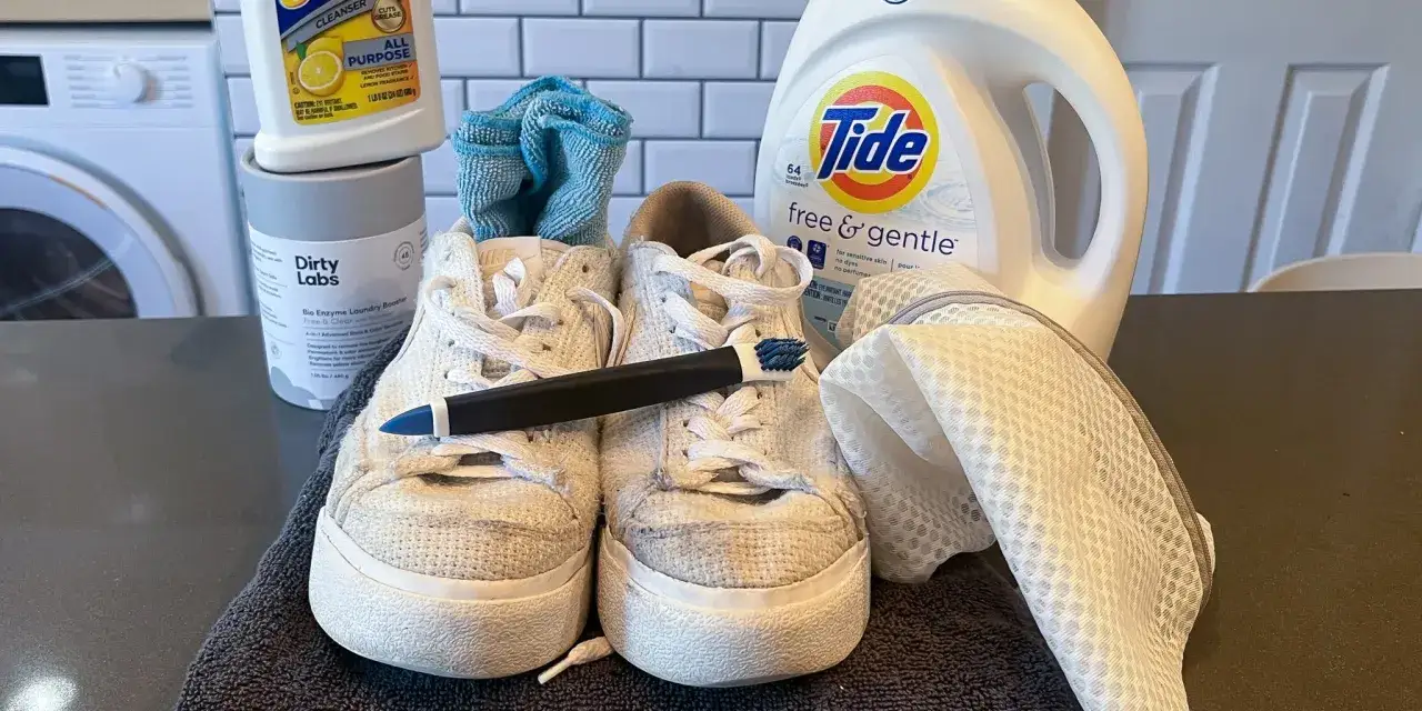 Vita sneakers redo för tvätt i diskmaskin. Tvättmedel, borste och tvättpåse redo.