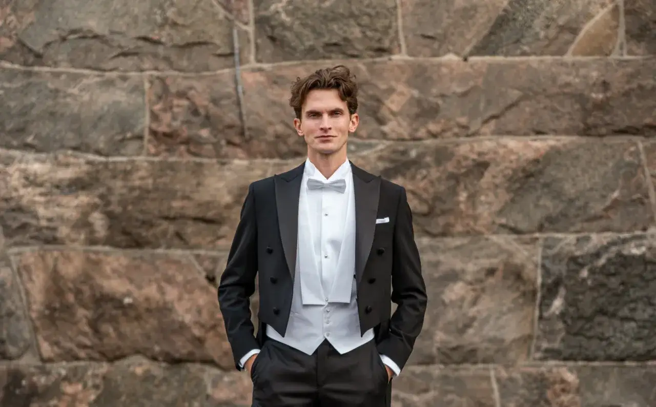 Man i frack med vit väst och fluga. Visar hur ska en frack sitta för en elegant look.