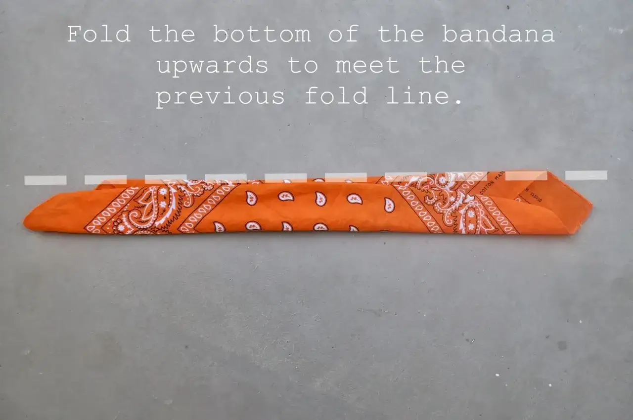 Orange bandana vikt p&aring; mitten. L&auml;r dig hur knyter man en bandana f&ouml;r en snygg stil.